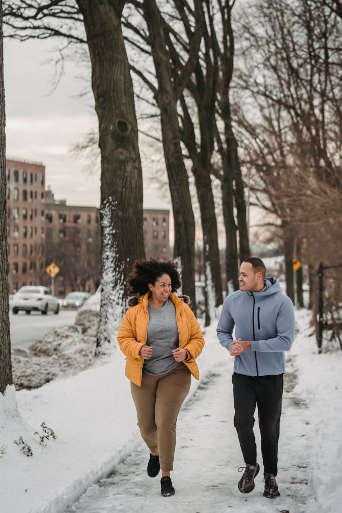 Cheerful trainer and black woman running in winter city park to support training zone for runners article